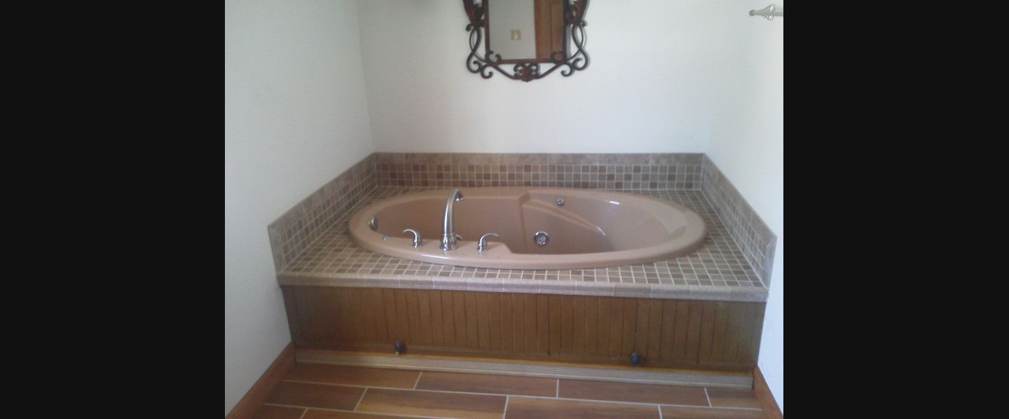 A bathroom with a jacuzzi tub and a mirror.