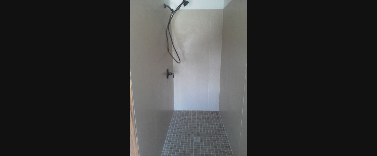 A bathroom with a shower head on the wall and a tiled floor.