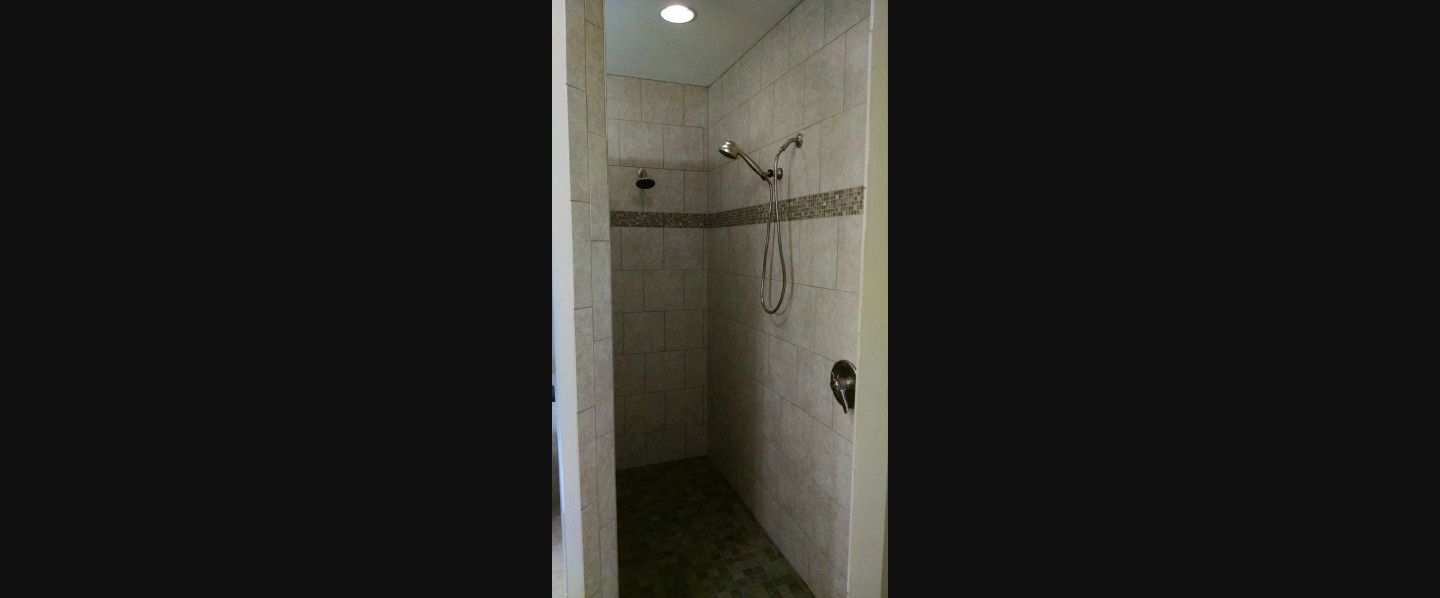 A bathroom with a walk in shower and a shower head.
