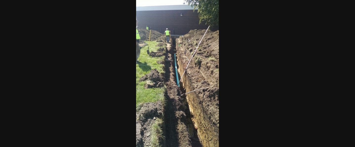 A group of people are digging a trench in the dirt.