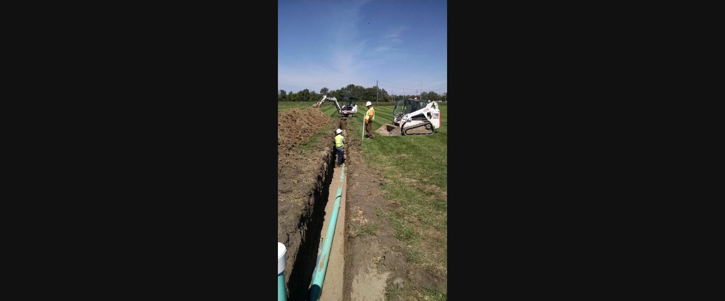 A group of people are working on a pipe in a field.