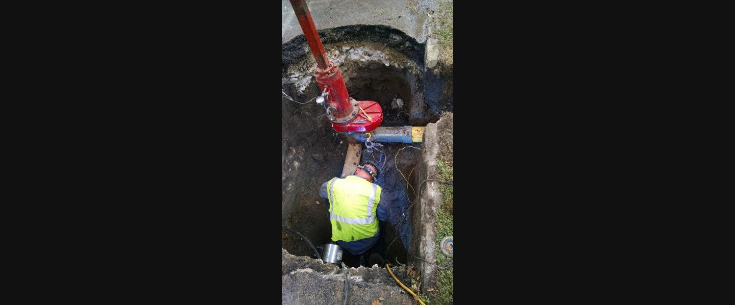 A man is working on a pipe in a manhole.