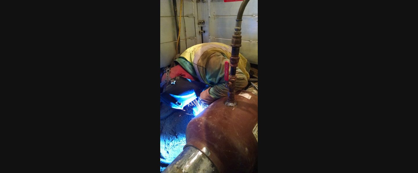 A man is welding a pipe in a room.