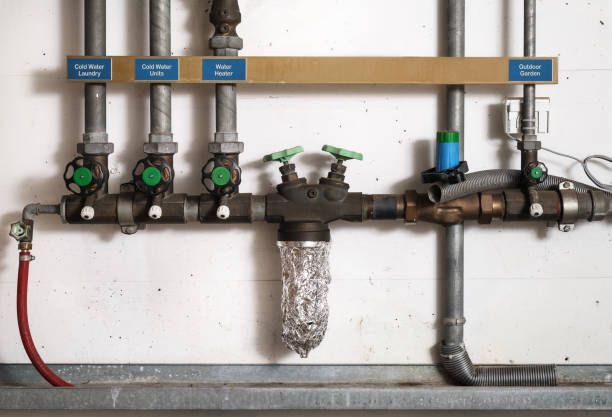 A close up of a row of pipes and valves on a wall.