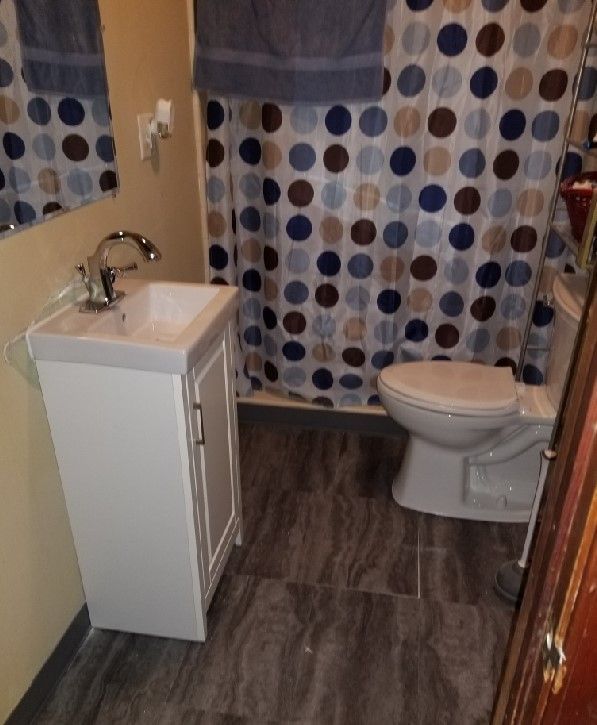 A bathroom with a toilet sink and polka dot shower curtain