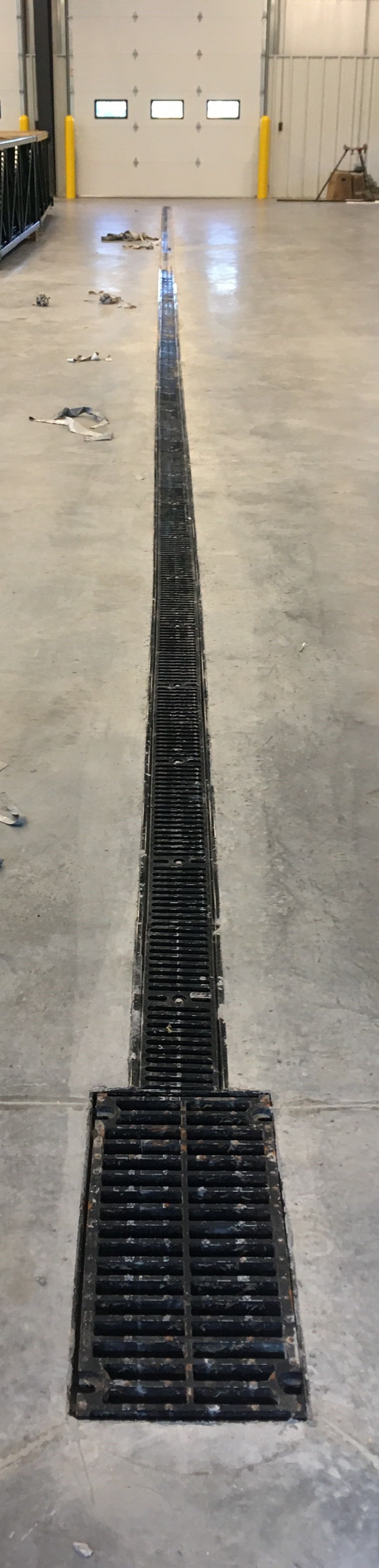 A drain in a warehouse with a garage door in the background.