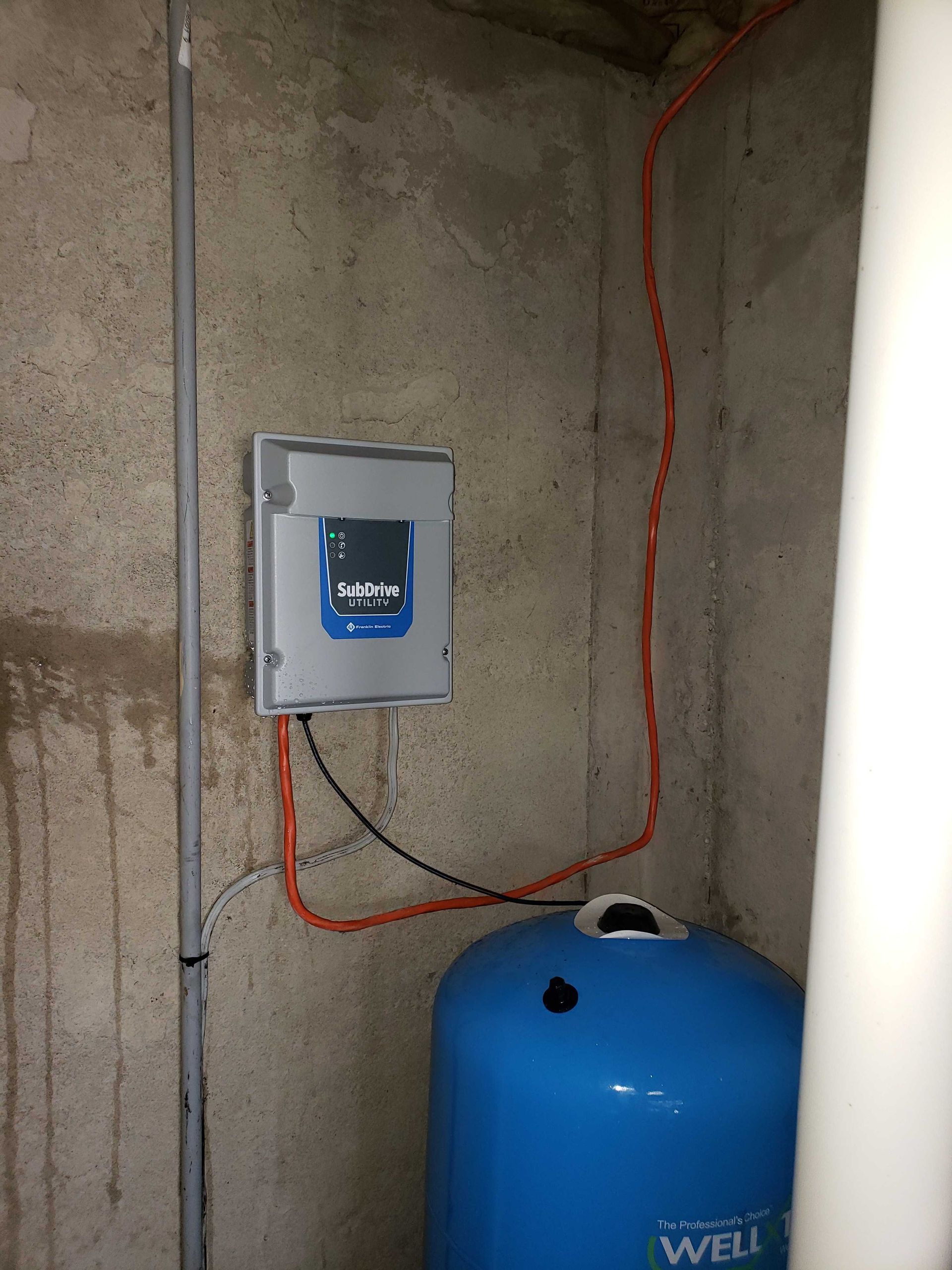 A blue water tank is sitting in a room next to a wall.