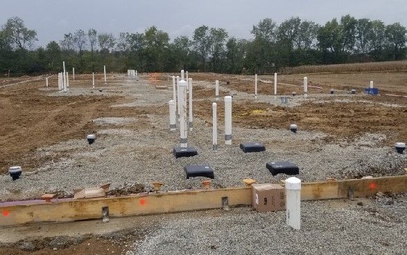 A construction site with a lot of pipes and trees in the background.