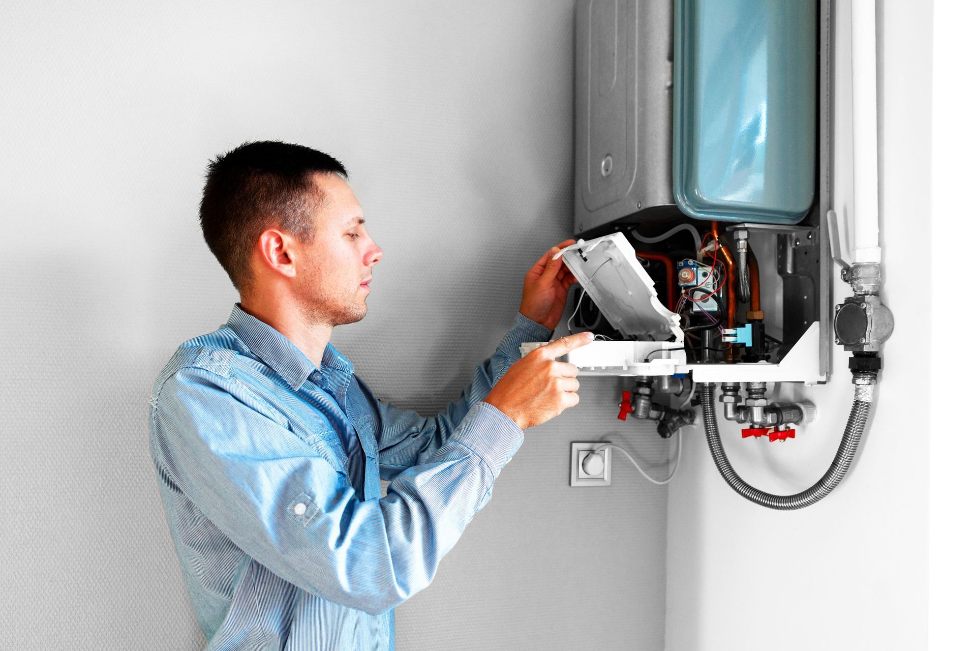 A man is fixing a water heater in a room.