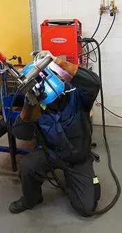 welder working inside shop to repair metal