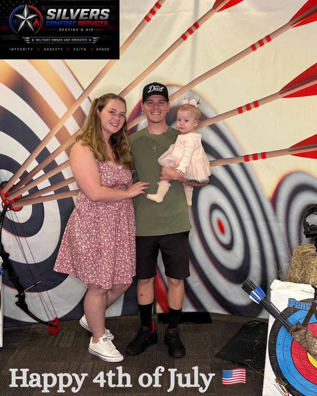 Family posing in front of a July 4th mural with American flag and target designs, “Happy 4th of July” text.