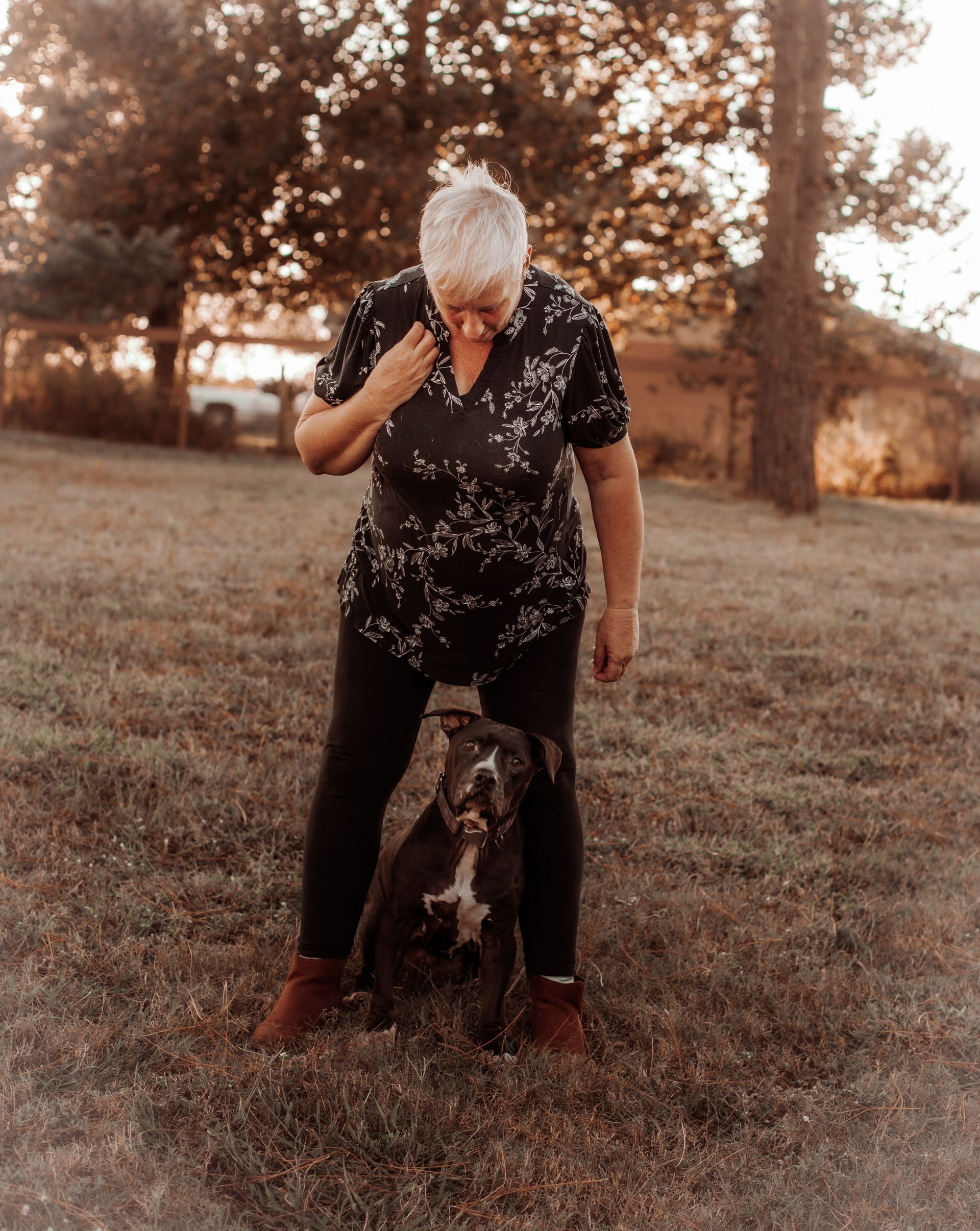 Young person crouching to greet a black dog on a park path