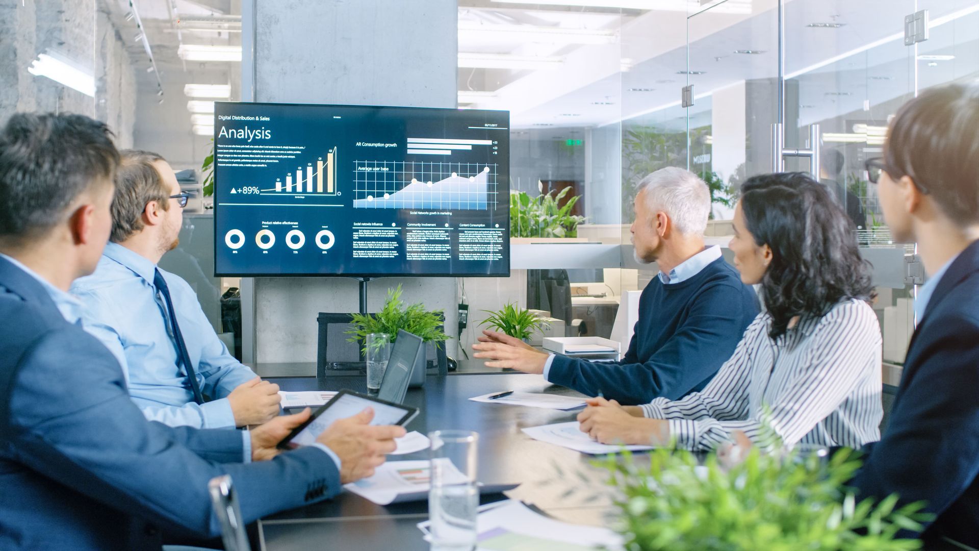 Business people in a meeting, analyzing financial data on a screen in an office.