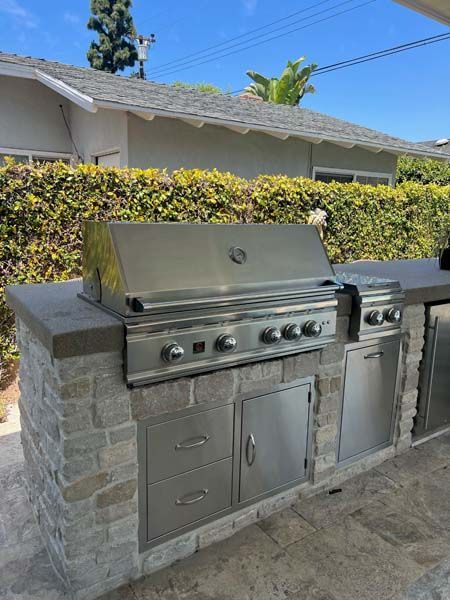 A stainless steel grill is sitting on top of a brick counter.