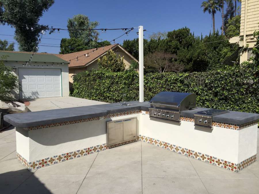 A patio with a grill and a garage in the background