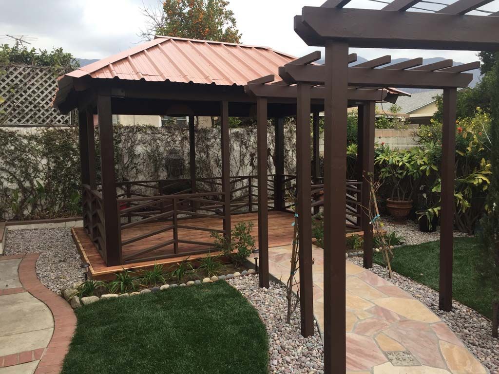 A gazebo with a copper roof is surrounded by a pergola