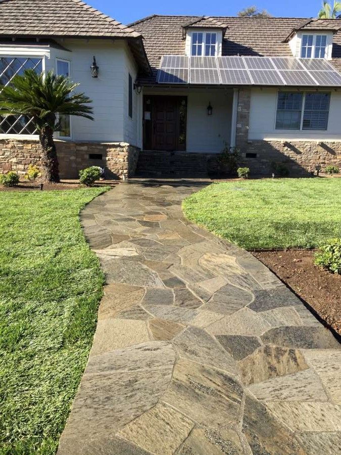 A stone walkway leading to a house with solar panels on the roof.