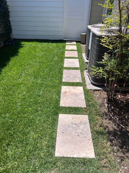 A stone walkway leading to a shed in a backyard.