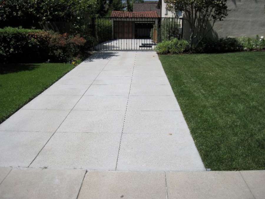 A concrete driveway leading to a house with a gate