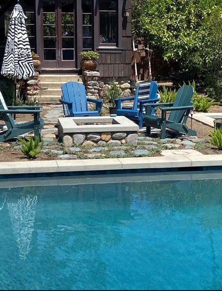 A swimming pool with blue chairs and a fire pit