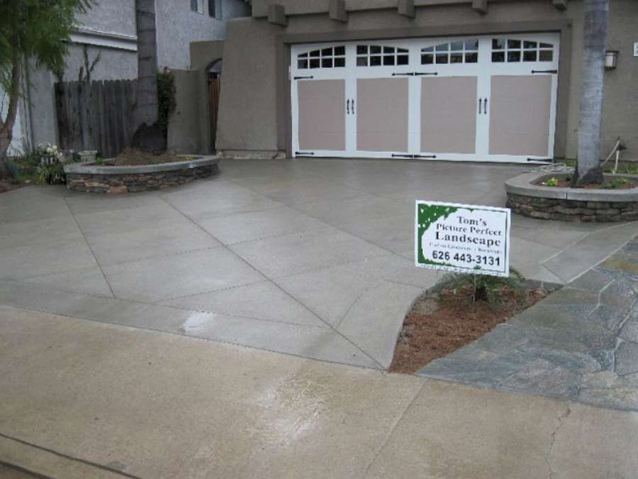 A concrete driveway with a sign in front of a garage