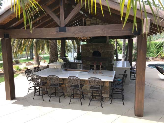 An outdoor kitchen with a fireplace and a flat screen tv.