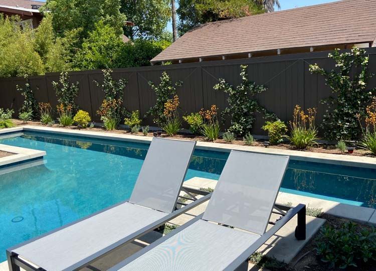Two lounge chairs are sitting next to a swimming pool.