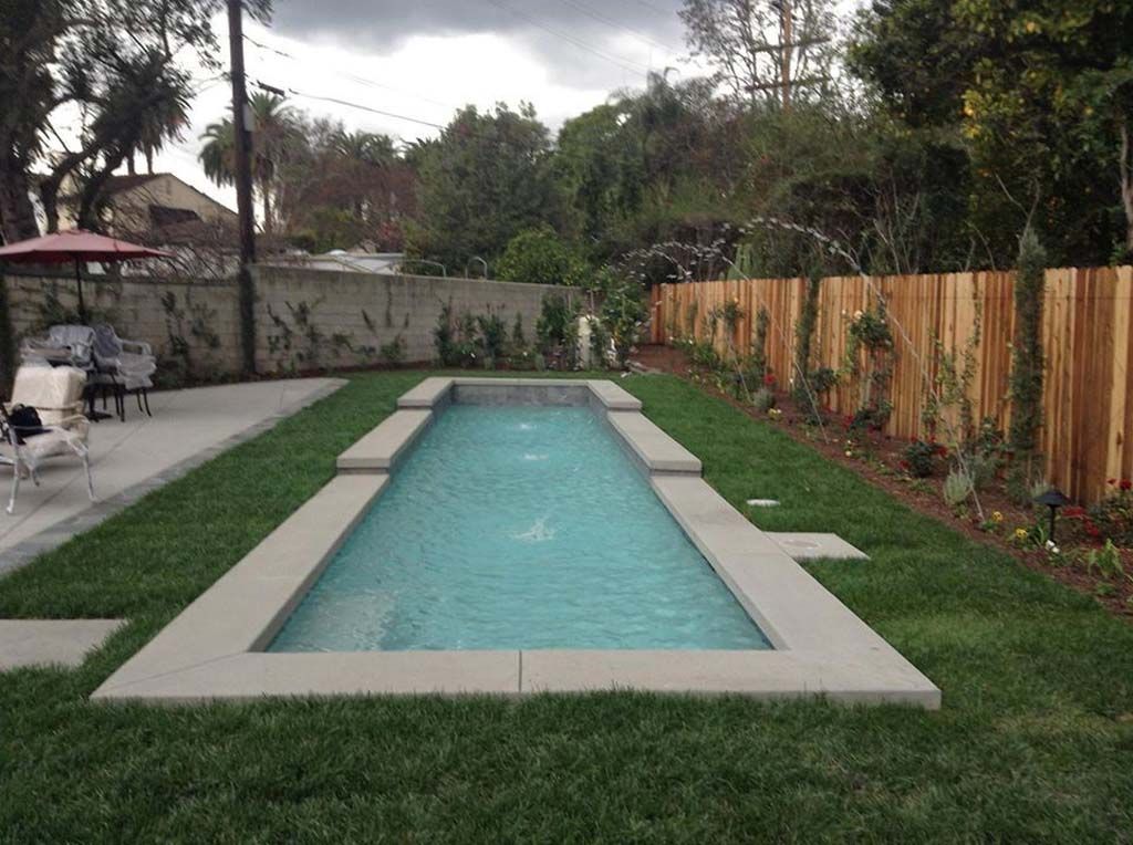 A large swimming pool in a backyard with a wooden fence