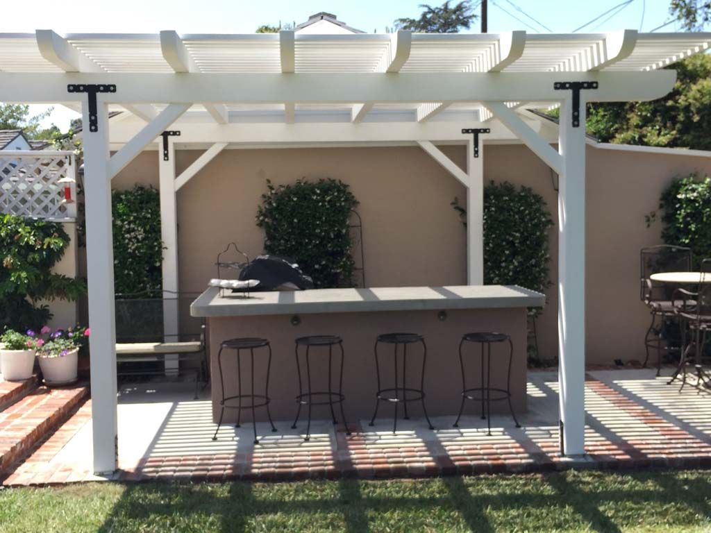 A pergola with a bar and stools underneath it