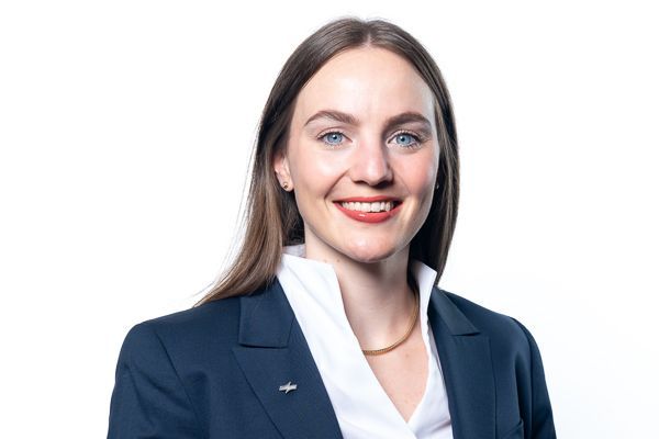Lächelnder Geschäftsmann in marineblauem Blazer und weißer Bluse vor weißem Hintergrund