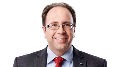 Lächelnder Mann im Anzug mit roter Krawatte vor weißem Hintergrund