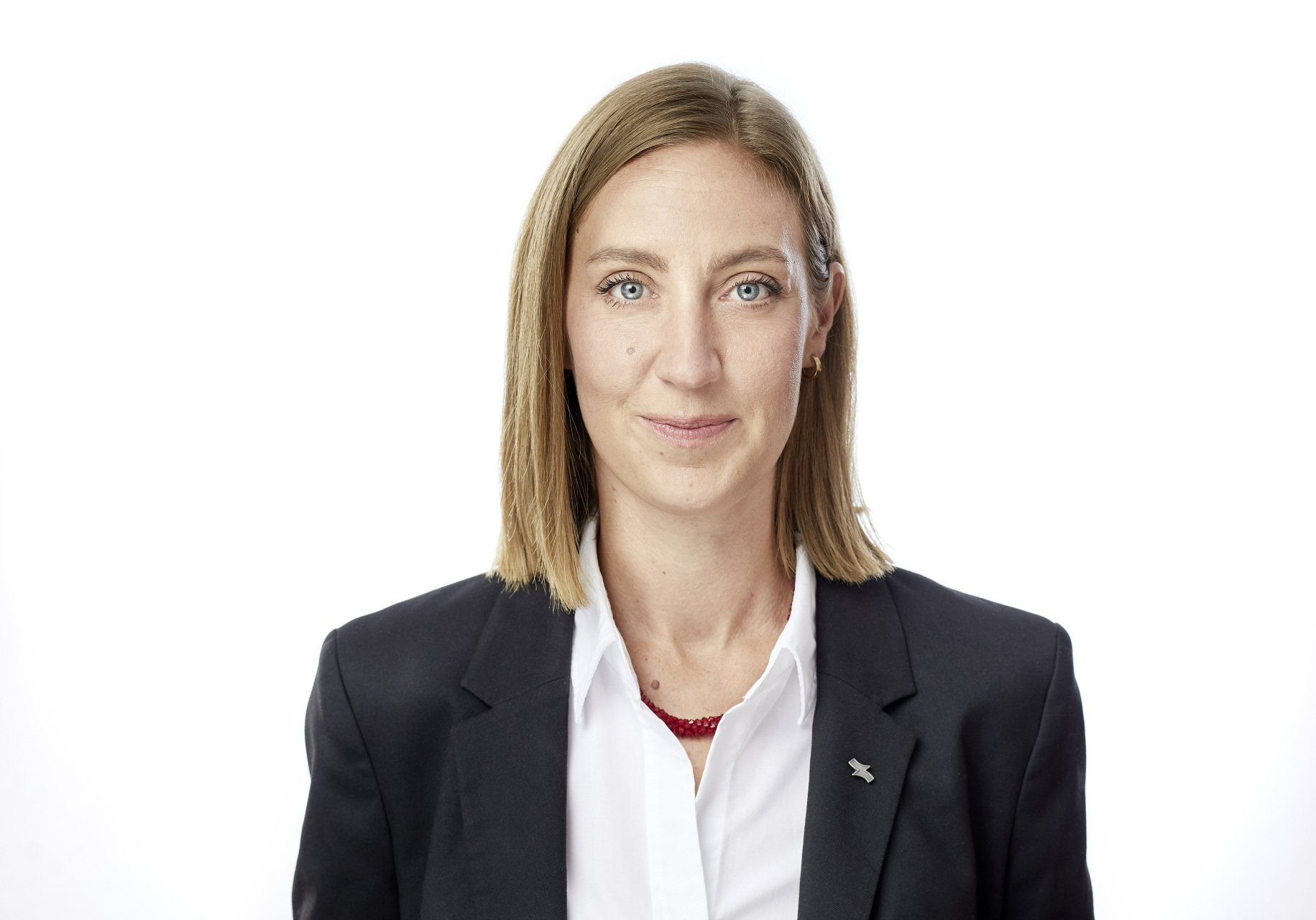 Porträt einer Person in schwarzem Blazer und weißem Hemd vor weißem Hintergrund (Kopf und Schultern)