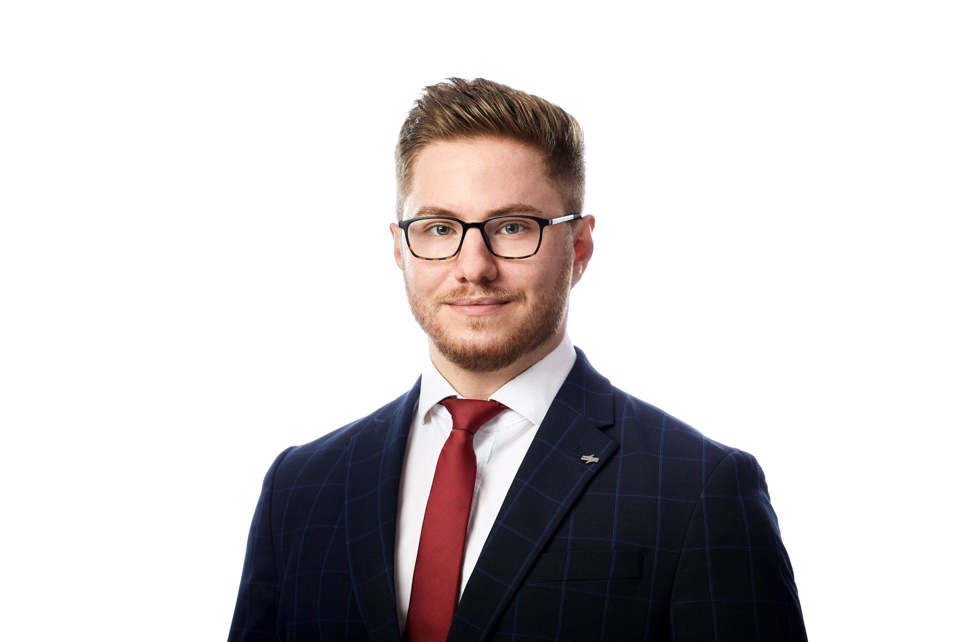 Porträt eines Mannes mit Brille, der einen dunkelblauen Anzug und eine rote Krawatte trägt, vor weißem Hintergrund