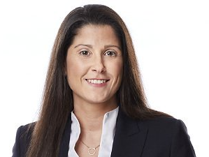 Porträt einer lächelnden Geschäftsfrau in einem dunklen Blazer und einer weißen Bluse vor weißem Hintergrund