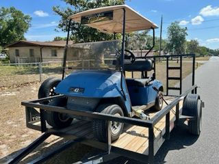 Trailer hitch with metal tow bar attached to a small trailer on a brick-paved surface