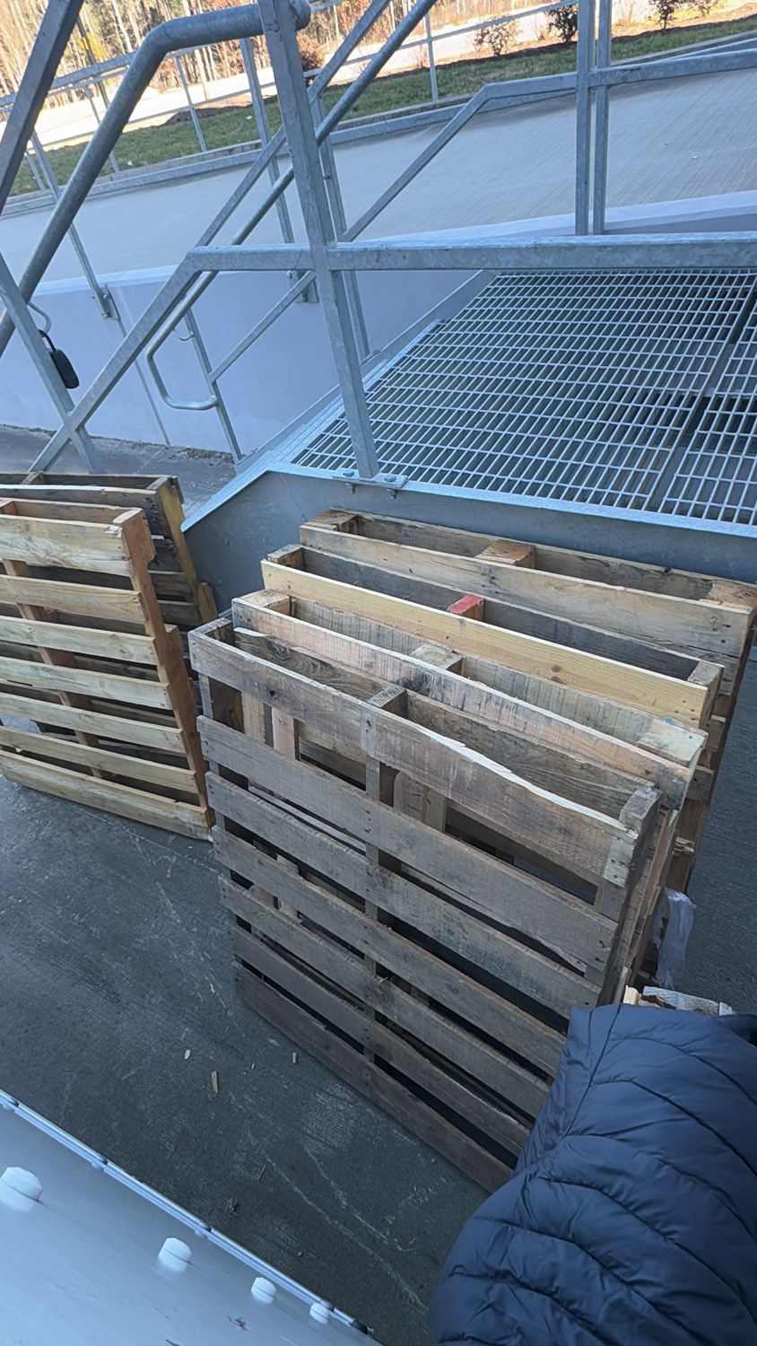Wooden pallets stacked beside a metal staircase and platform in an industrial setting