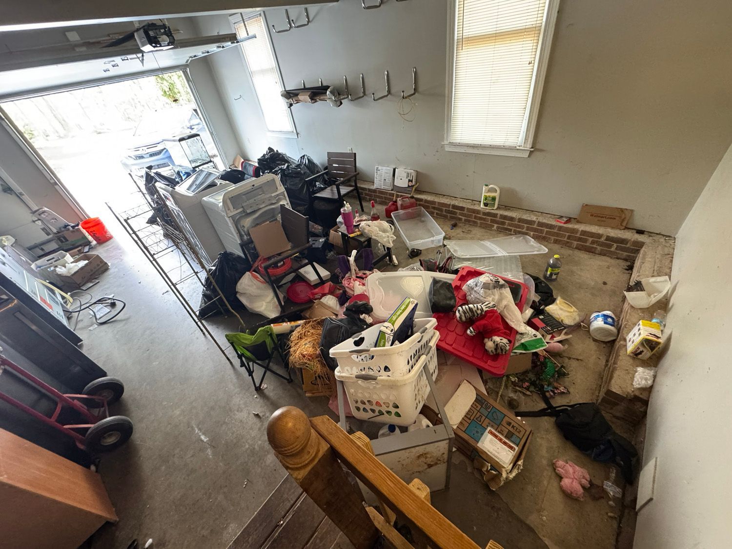 Living room filled with scattered items, boxes, and trash around a couch and stairs