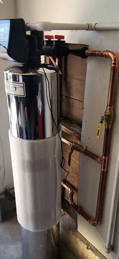 Water softener system with copper pipes on a wall.