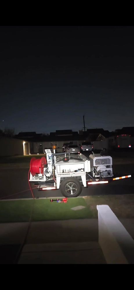 White utility truck parked on a grassy strip at night with houses in the background.