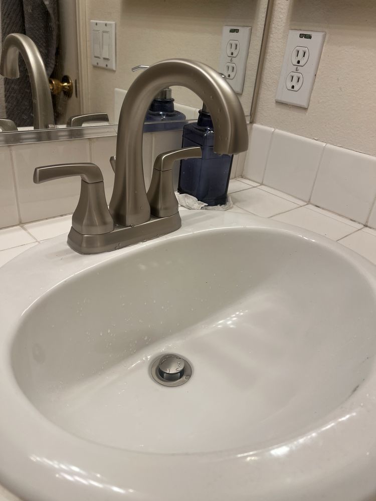 White sink with silver faucet and handles. Soap dispenser on the counter.
