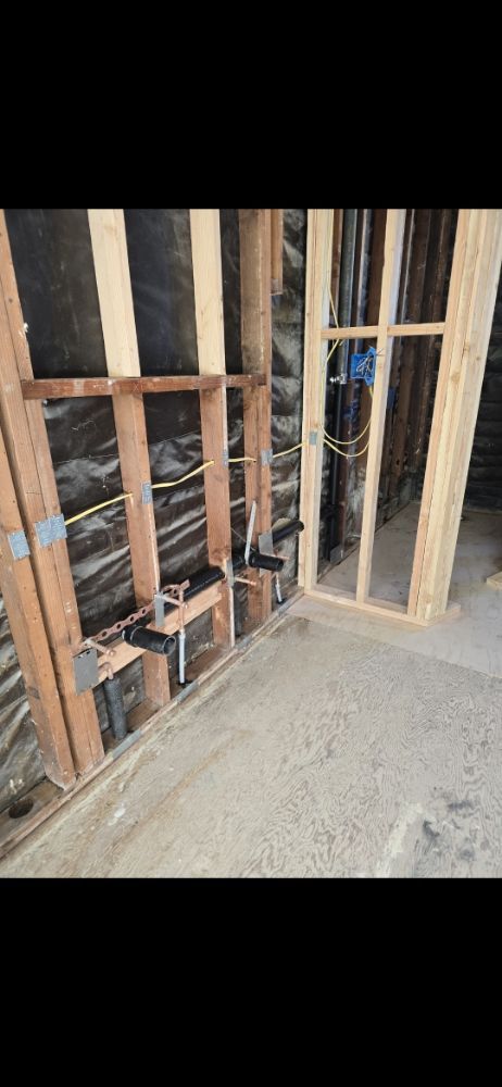 Framed walls with plumbing and electrical wiring; construction site.