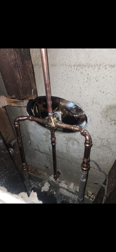 Copper pipes installed against a concrete wall.