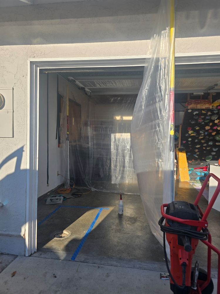 Garage interior with clear plastic barrier, blue tape on the floor, and tools.