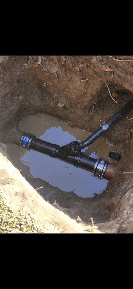 Pipes and fittings in a hole filled with water, in the ground.