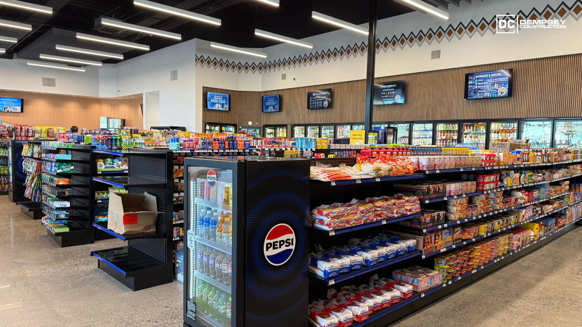 Interior of a convenience store with shelves stocked with snacks and drinks, illuminated by bright overhead lights.