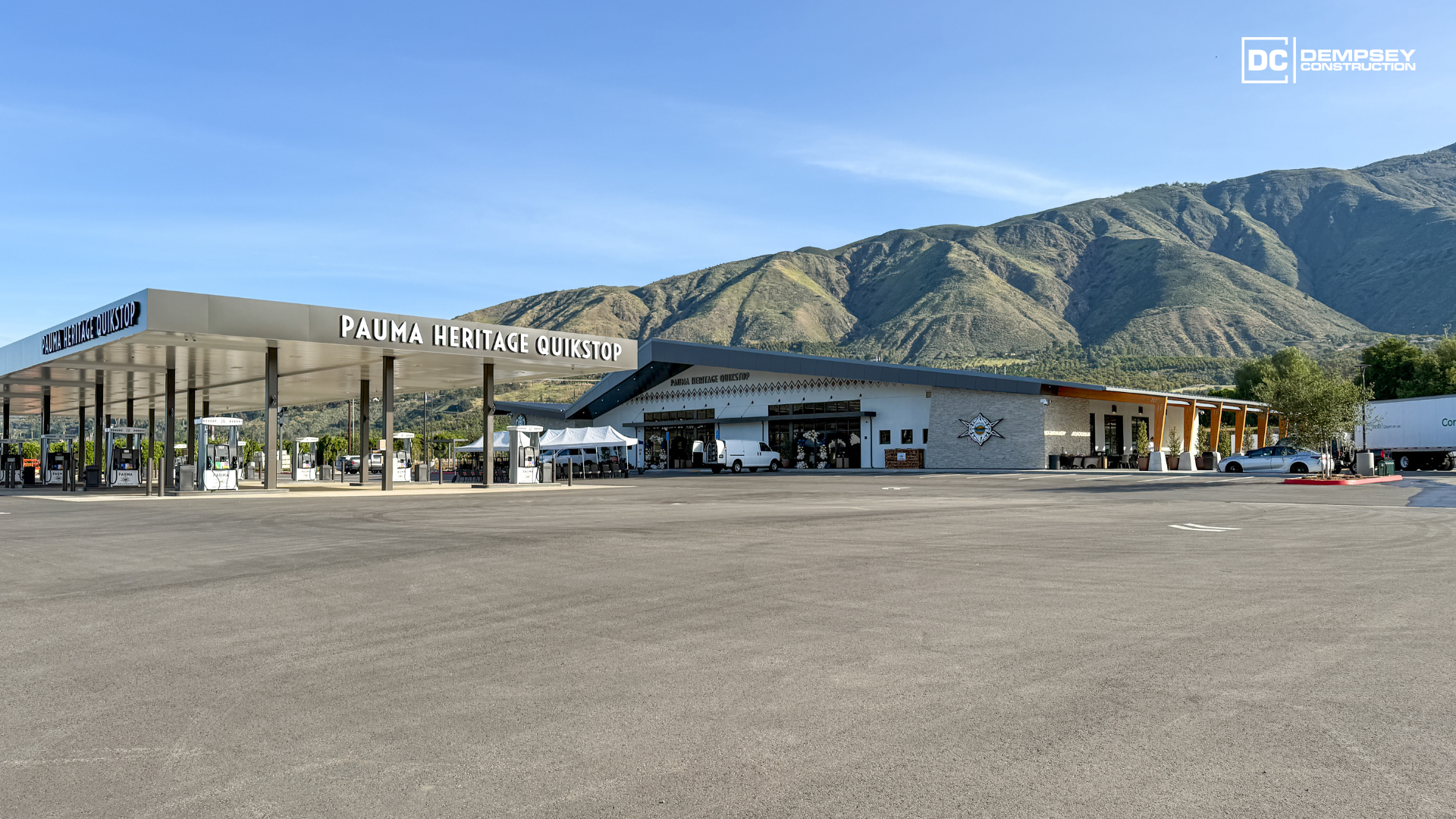 A gas station and adjacent convenience store situated in a dry, mountainous landscape under a clear blue sky.