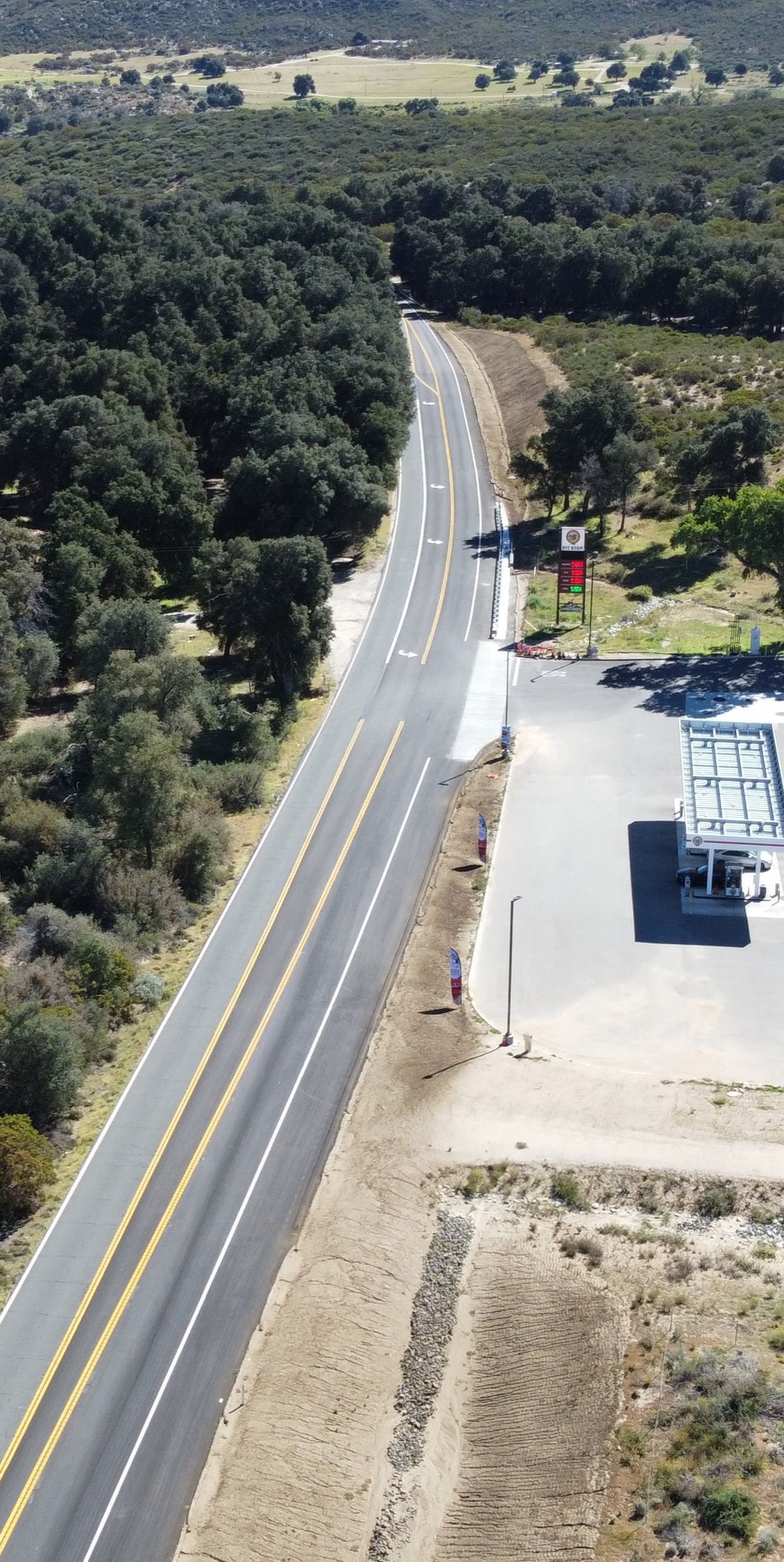 An aerial view of a highway surrounded by trees and a gas station.