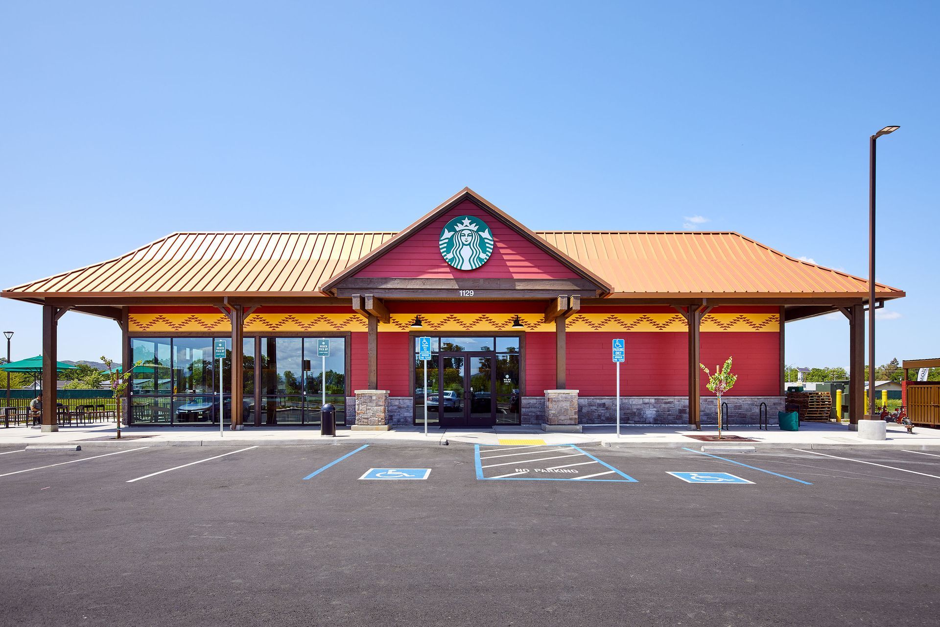 Front view of a red and tan storefront with a parking lot and blue sky
