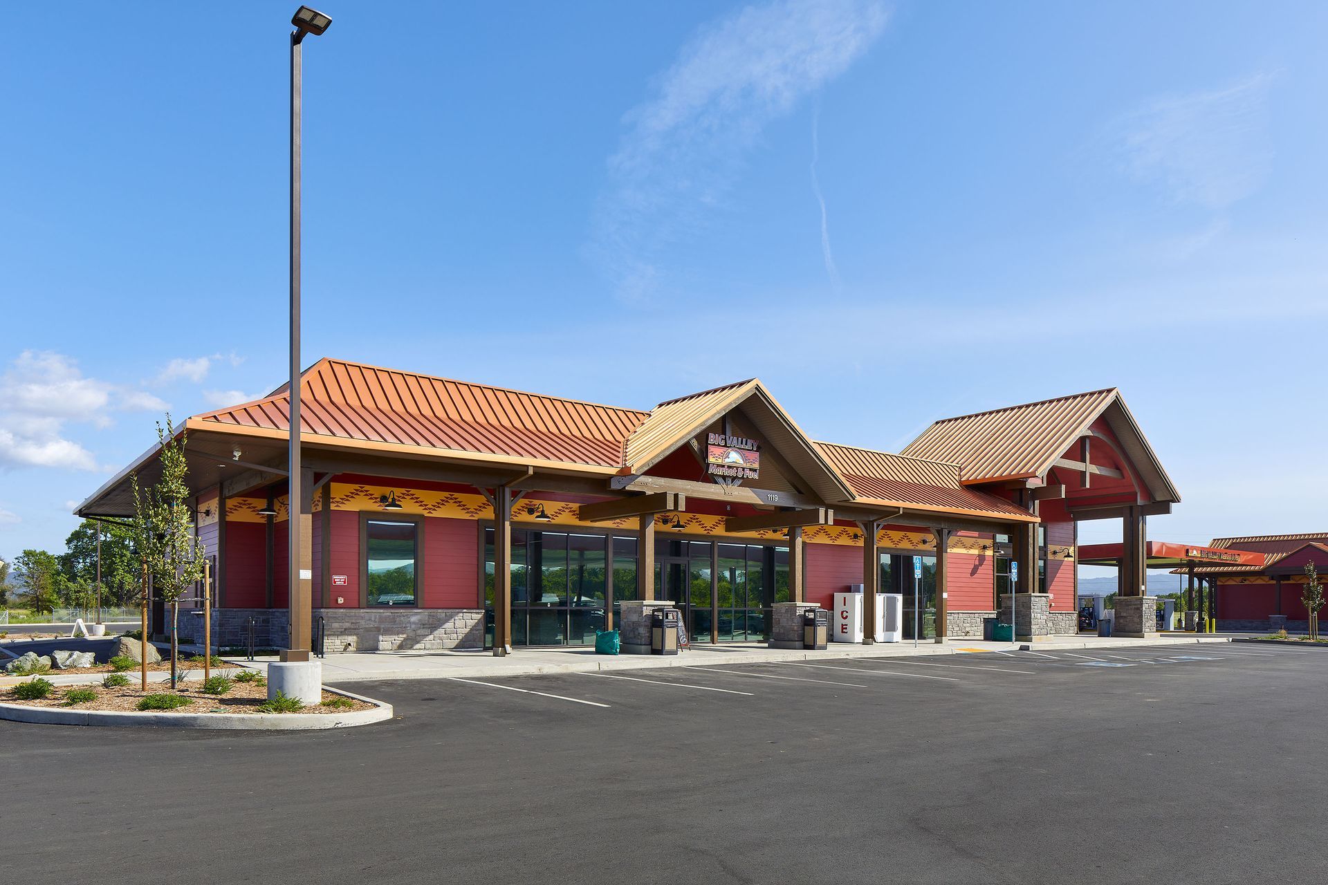 A rendering of a gas station with a convenience store, brown and red brick building, with gas pumps in the foreground.