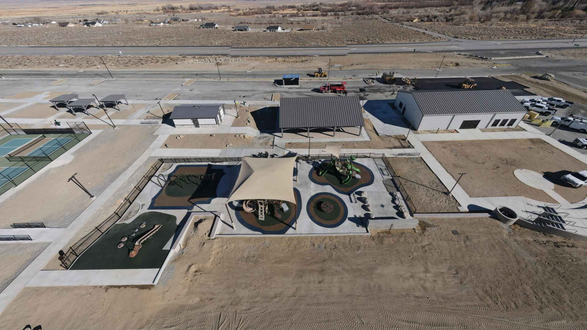 Aerial view of a desert park featuring a playground, tennis courts, and several buildings.